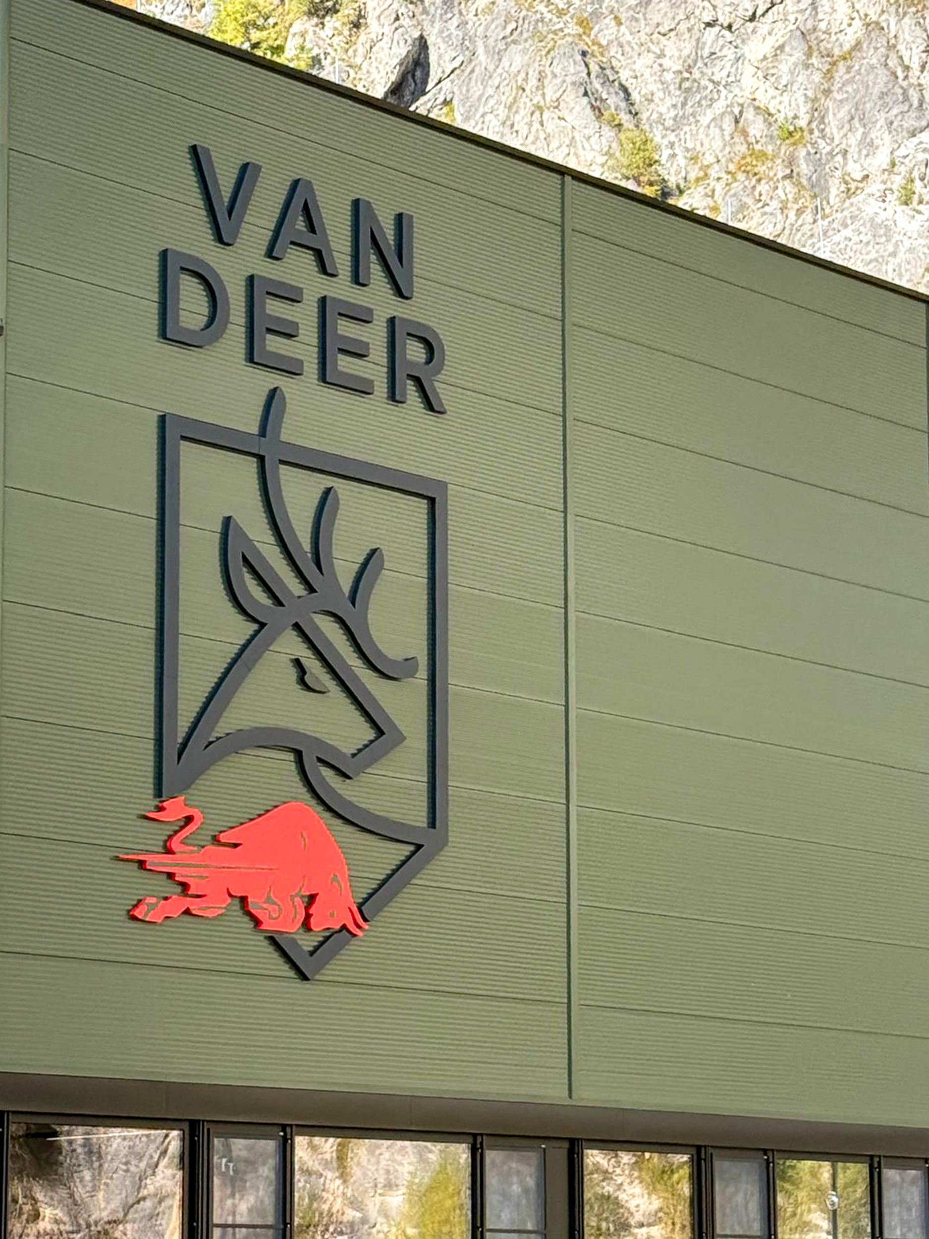 Logo von VAN DEER mit einem stilisierten Reh und rotem Element an einer Wand.